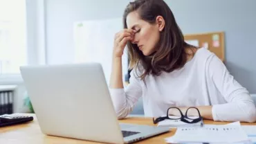 mujer cansada frente a computadora